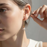 Close-up of a woman wearing a delicate earring with a neutral background