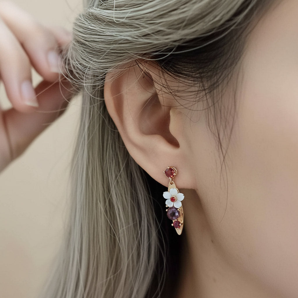 Close-up of an ear wearing a floral earring with colorful stones.