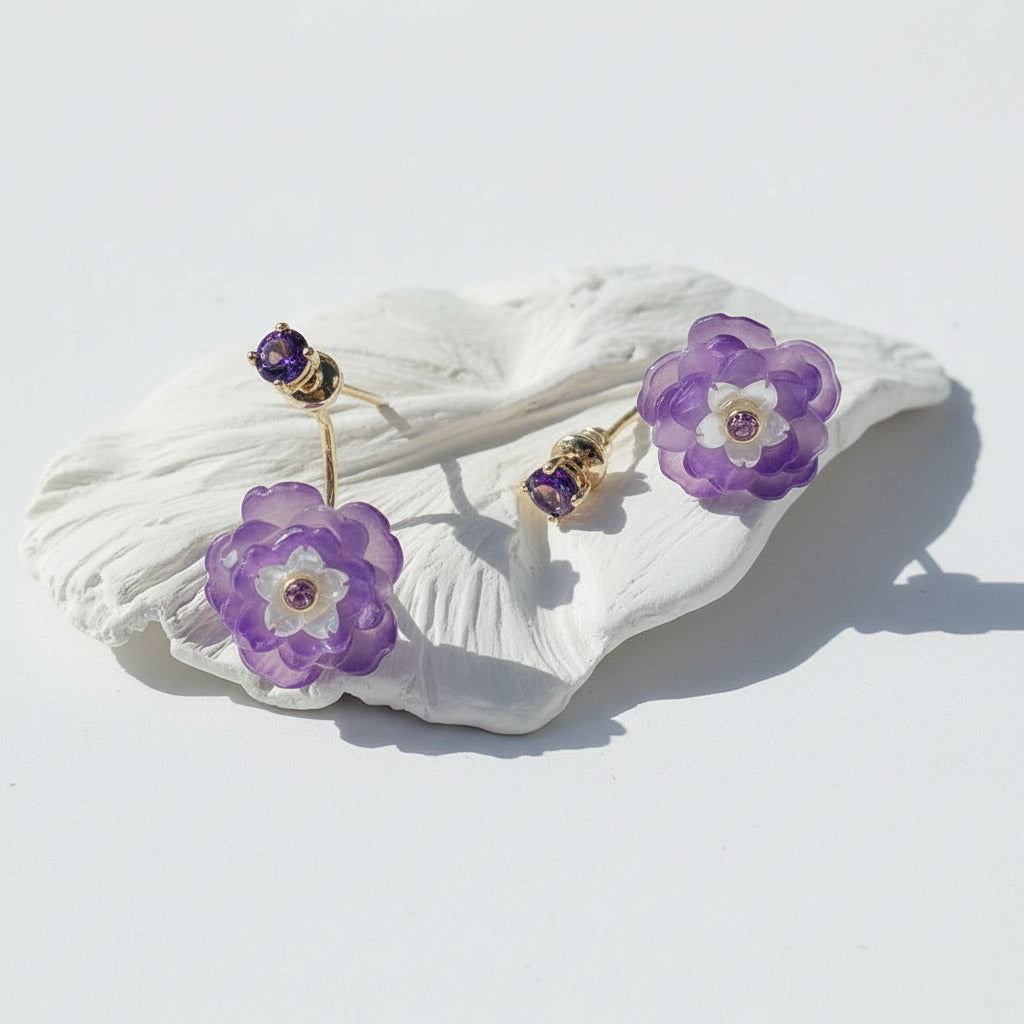 Purple flower-shaped earrings on a white shell against a white background