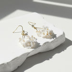 Floral earrings on a white stone surface with soft shadows