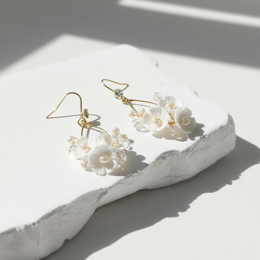 Floral earrings on a white stone surface with soft shadows