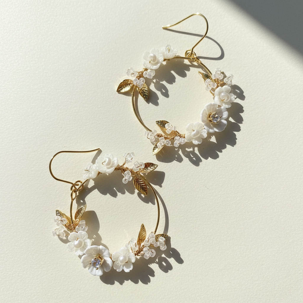Gold hoop earrings with floral and leaf designs on a light background