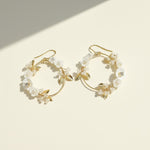 Gold hoop earrings with floral designs on a beige background
