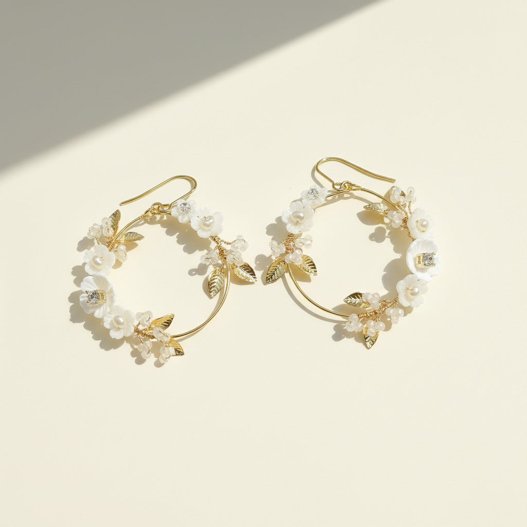 Gold hoop earrings with floral designs on a beige background