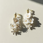 Floral earrings with white flowers and gold accents on a light background