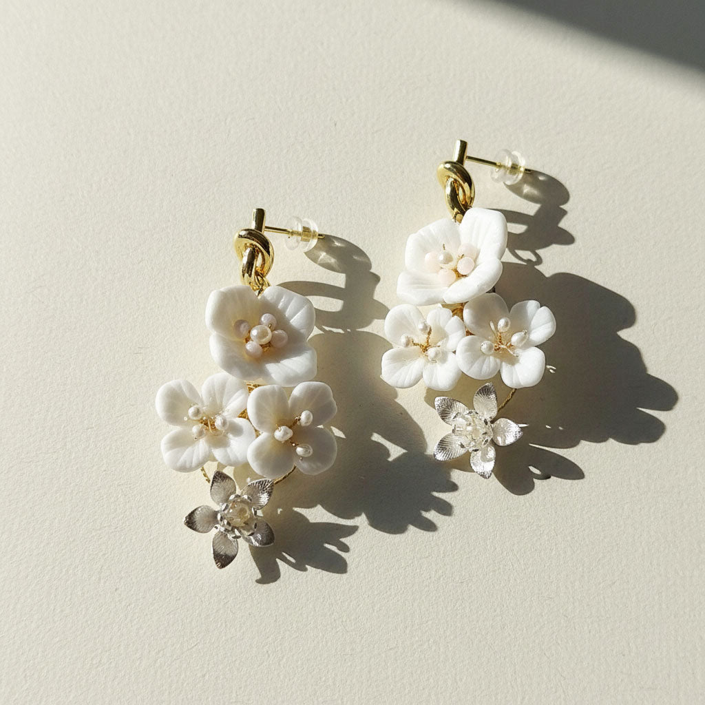 Floral earrings with white flowers and gold accents on a light background
