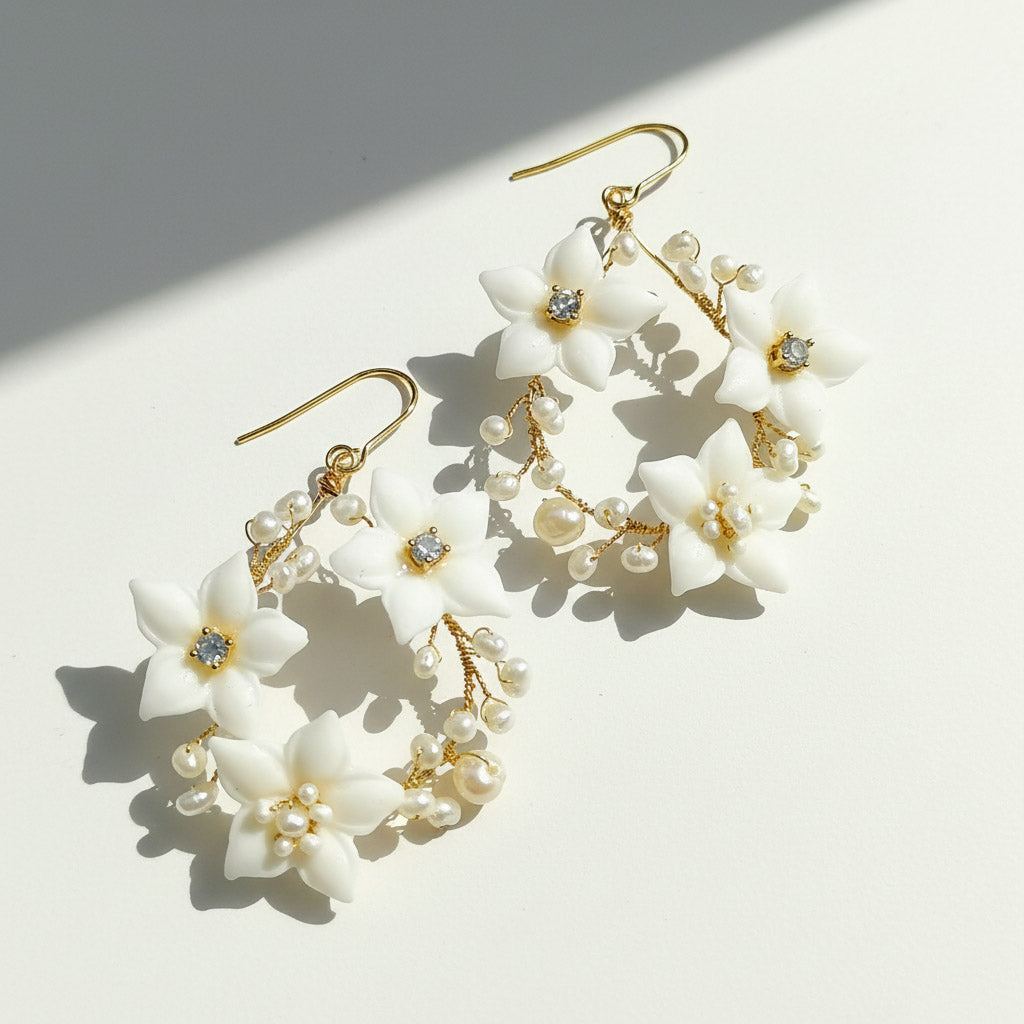 Floral earrings with white flowers and gold accents on a light background