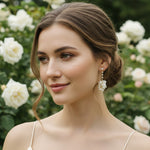 Model wearing porcelain flower and pearl drop earrings in garden setting.