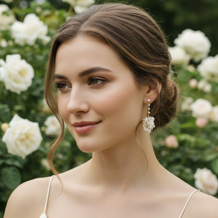 Model wearing porcelain flower and pearl drop earrings in garden setting.