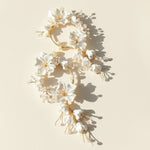 Floral headpiece with white flowers and gold accents on a beige background