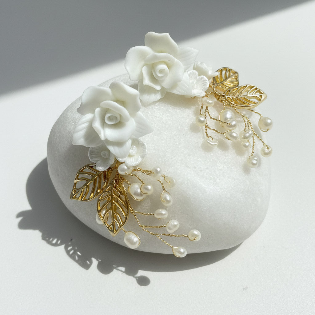 Decorative earrings with white flowers, gold leaves, and pearls on a white background