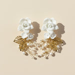Pair of floral earrings with gold leaves and pearls on a beige background