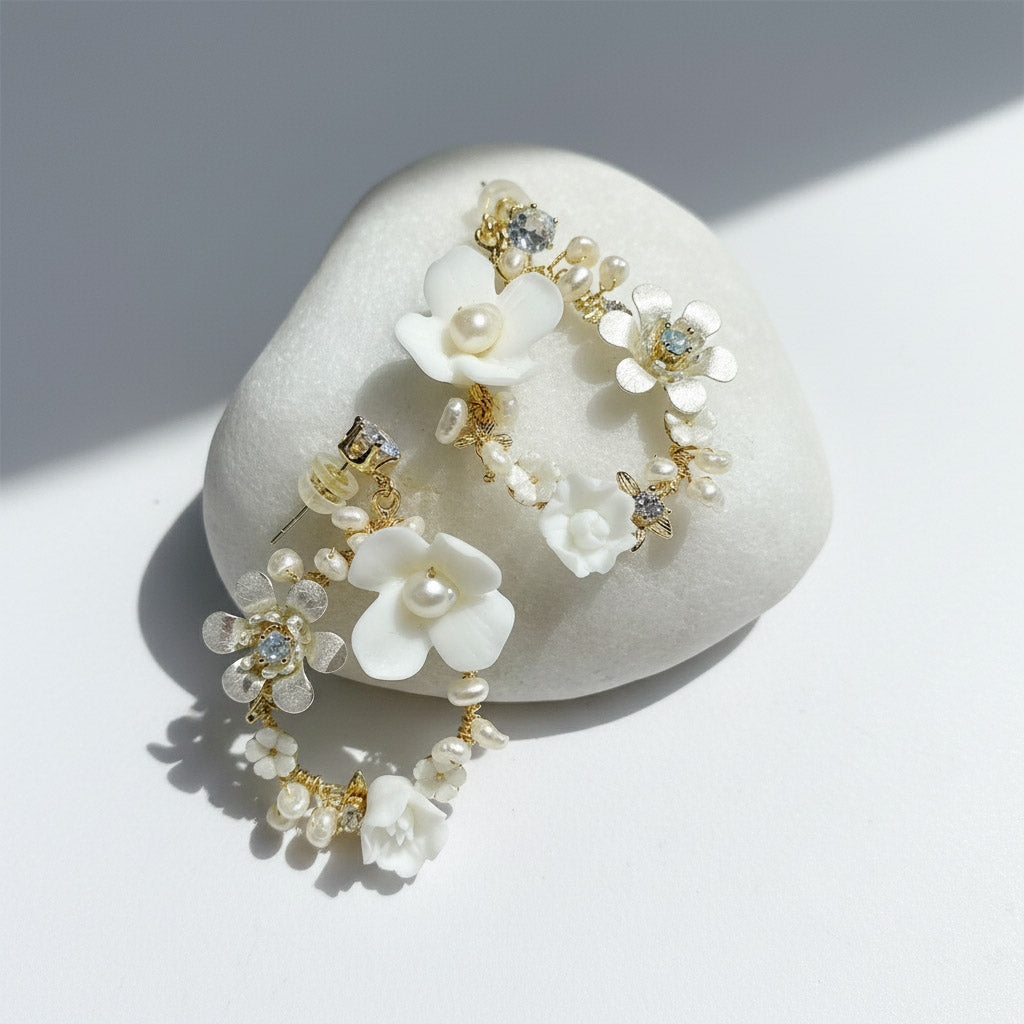 Porcelain floral and pearl hoop earrings on white background with sunlight and shadow.