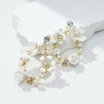 Close-up of porcelain flower hoop earrings with freshwater pearls and gold-plated finish.