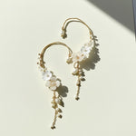 Floral pearl ear climber earrings on ivory background with sunlight and shadow.