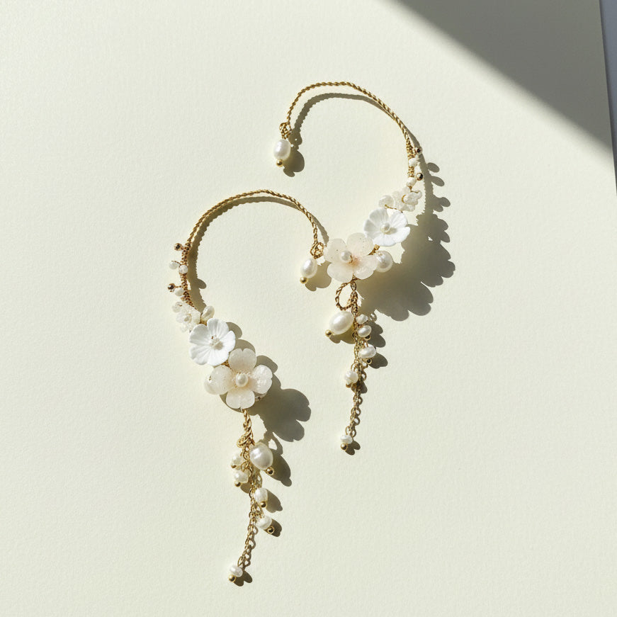 Floral pearl ear climber earrings on ivory background with sunlight and shadow.