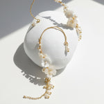 Close-up of resin flower and pearl ear climber earrings with gold-plated detail.