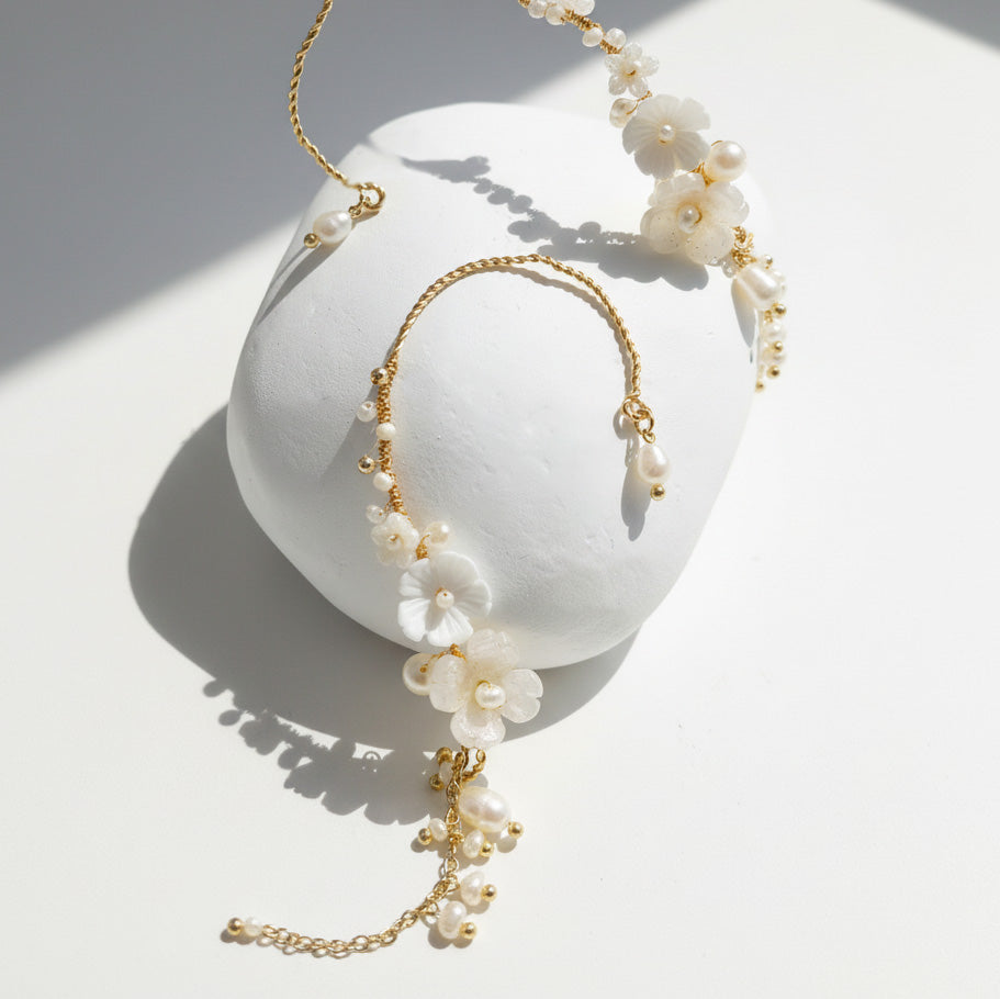 Close-up of resin flower and pearl ear climber earrings with gold-plated detail.