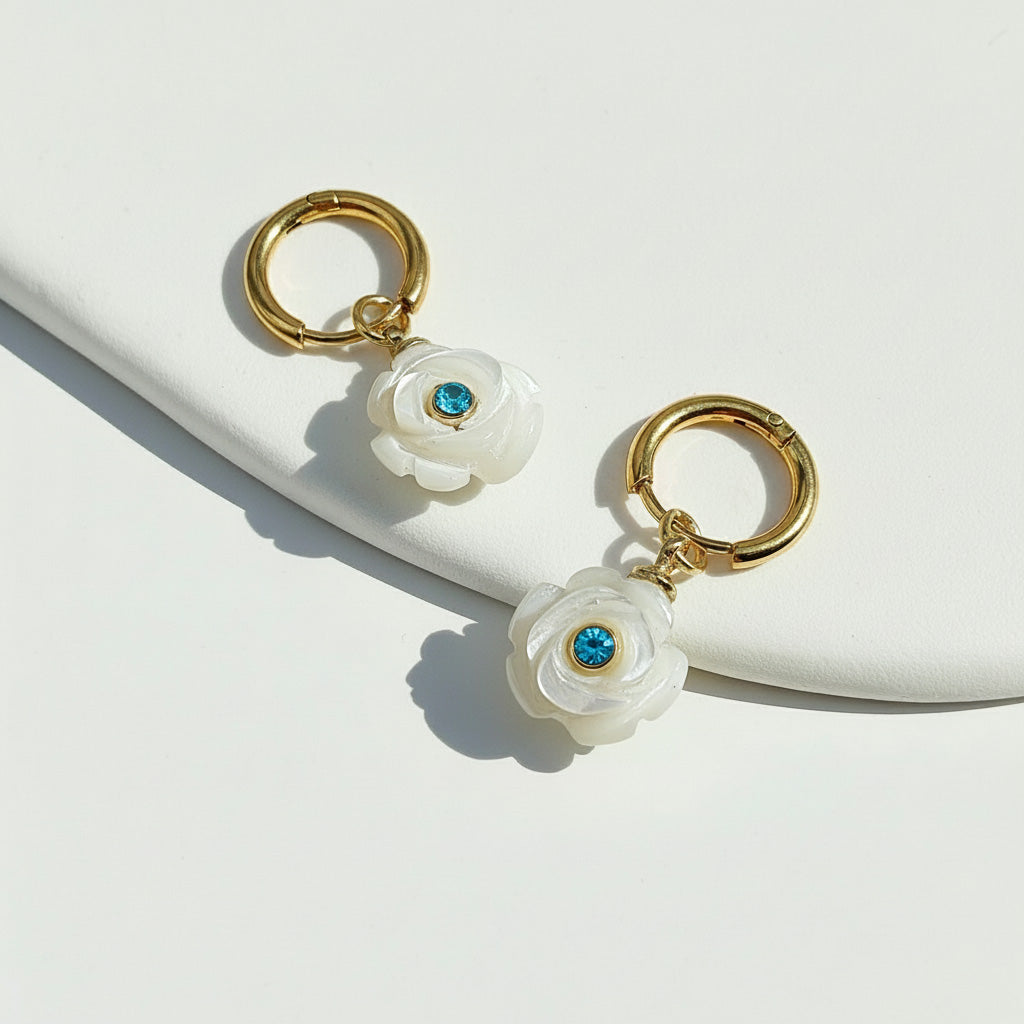 Pair of earrings with white floral designs and gold accents on a light background