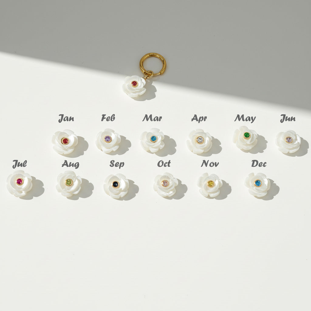 Set of white flower-shaped charms with colored stones for each month on a light gray background.