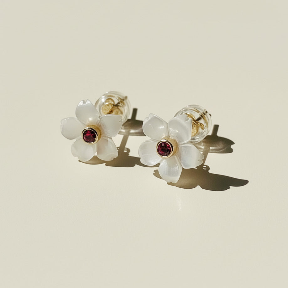 Flower-shaped earrings with red gemstones on a beige background