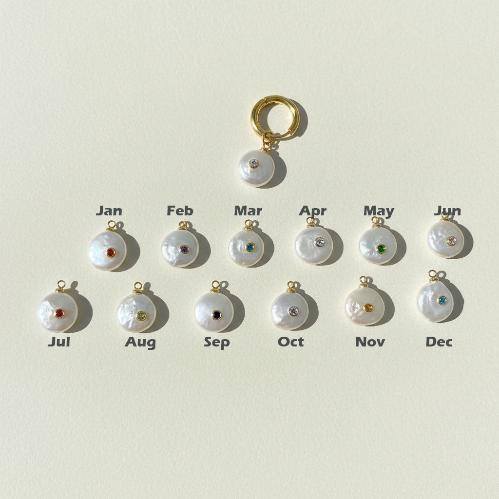 Pearl charms with gemstones labeled for each month on a light background