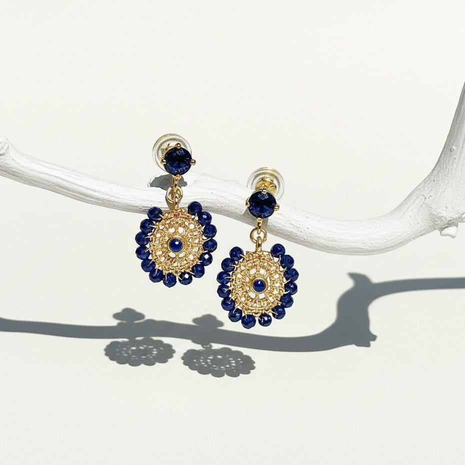 Gold and navy blue beaded dangle earrings with circular woven design hanging from crystal studs.