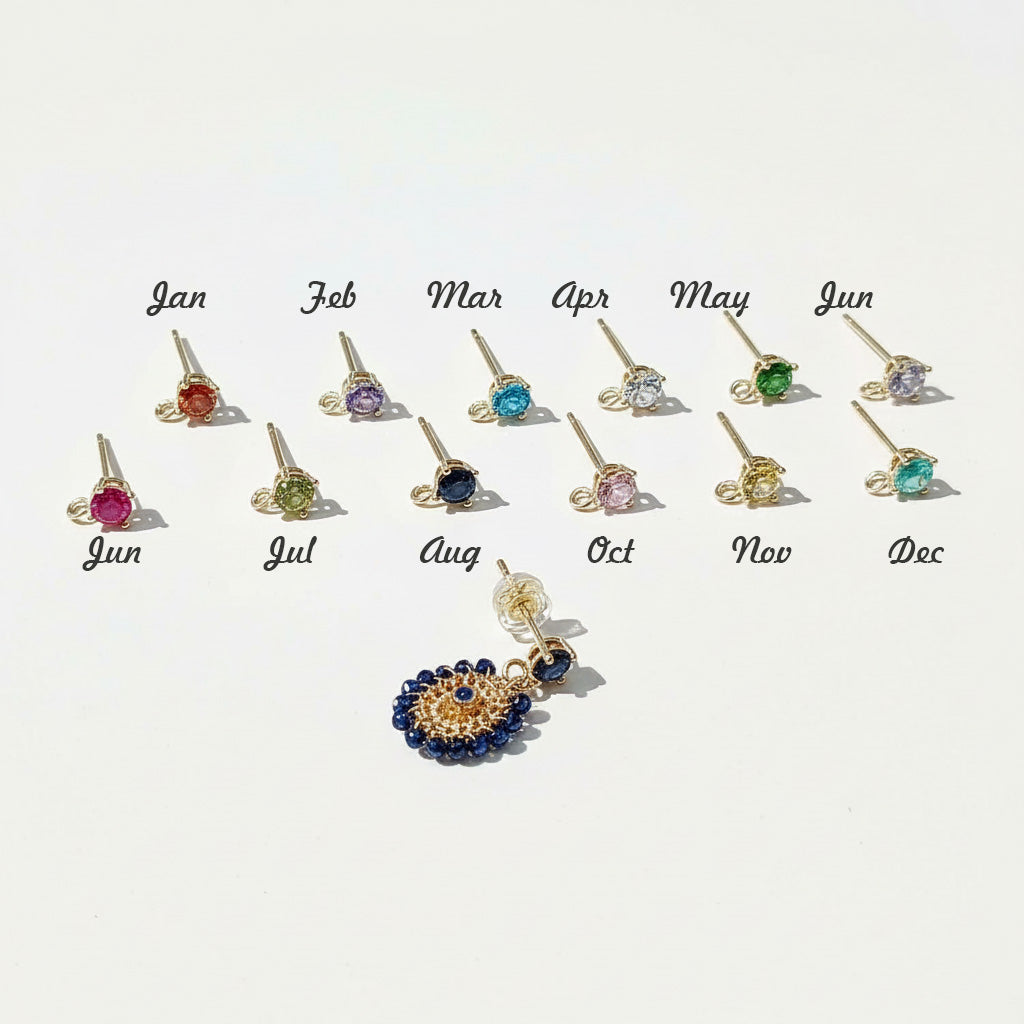 Custom birthstone earrings with interchangeable studs for each month shown beside gold and navy beaded dangle earring.