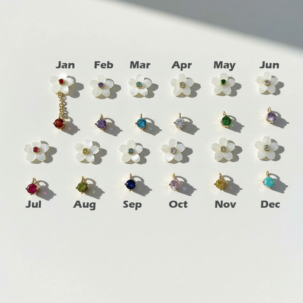 Set of floral earrings with colored gemstones corresponding to each month on a white background.