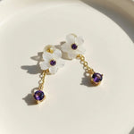 Floral earrings with purple gemstones on a white background