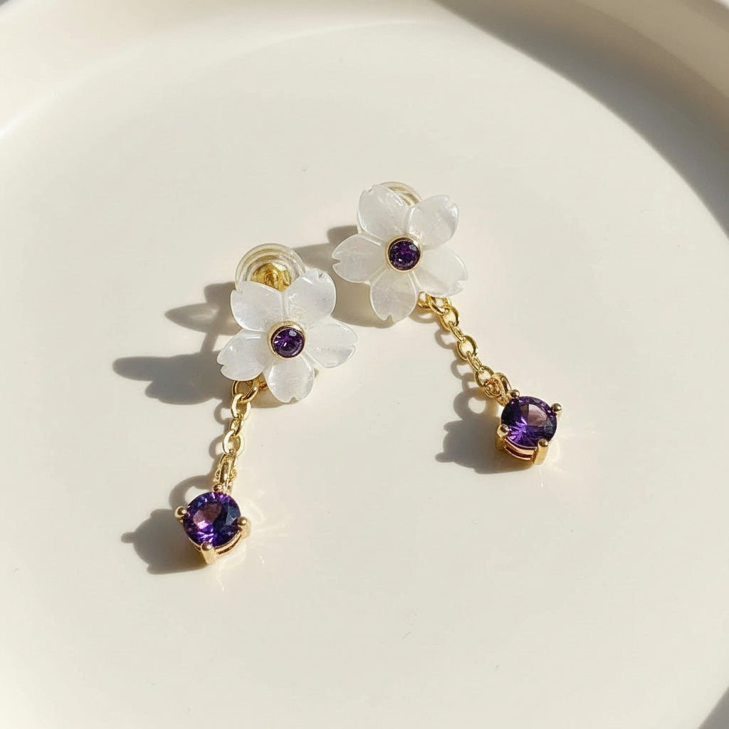 Floral earrings with purple gemstones on a white background