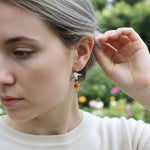 Woman wearing a unique earring with a blurred outdoor background