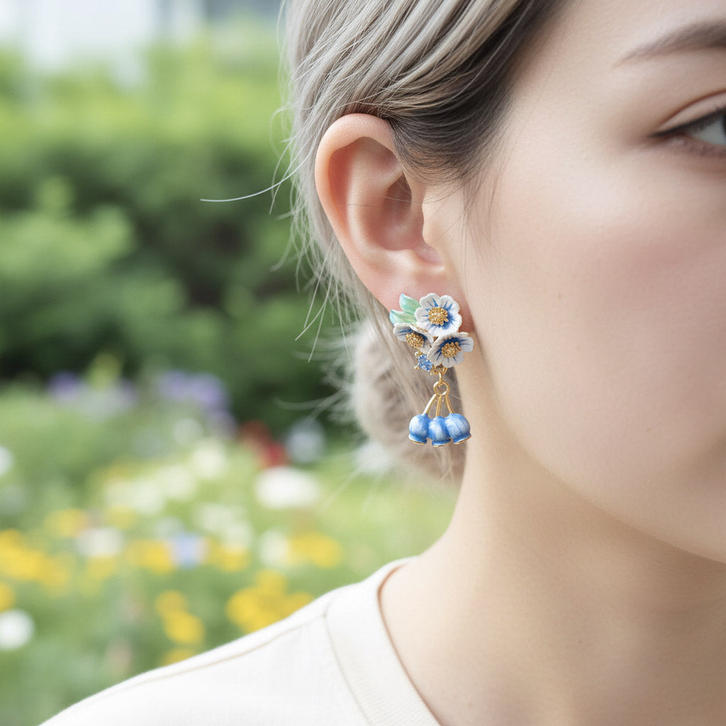 Close-up of a person wearing floral earrings with a blurred garden background