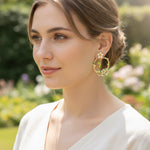 Woman wearing floral hoop earrings in a garden setting