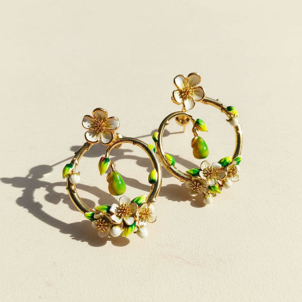 Gold hoop earrings with floral and green accents on a beige background