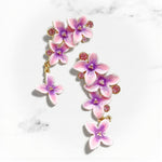 Floral earrings with pink and purple flowers on a marble background