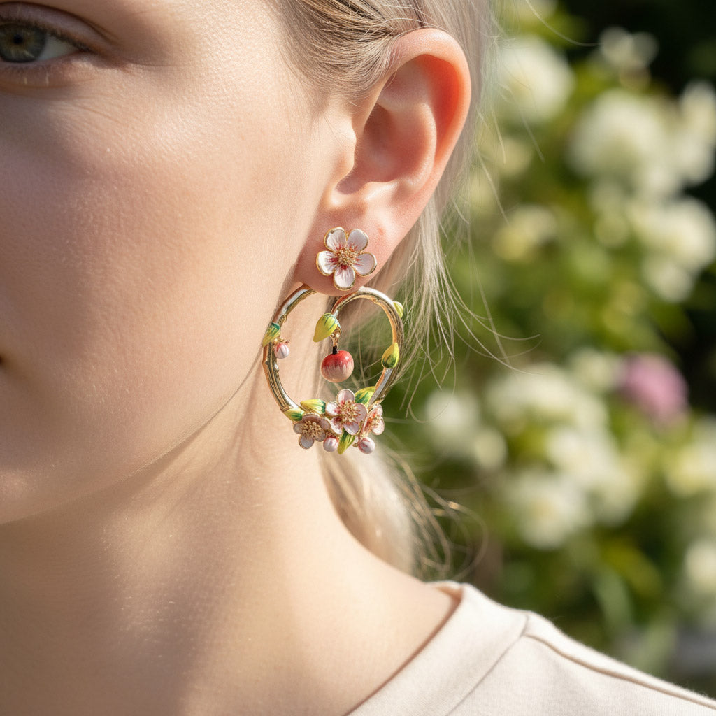 Close-up of a person wearing floral hoop earrings with a blurred floral background