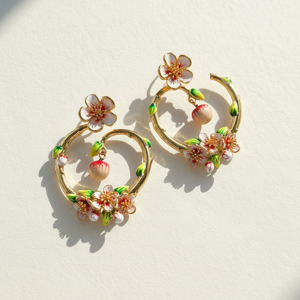 Pair of gold hoop earrings with floral and shell designs on a light background