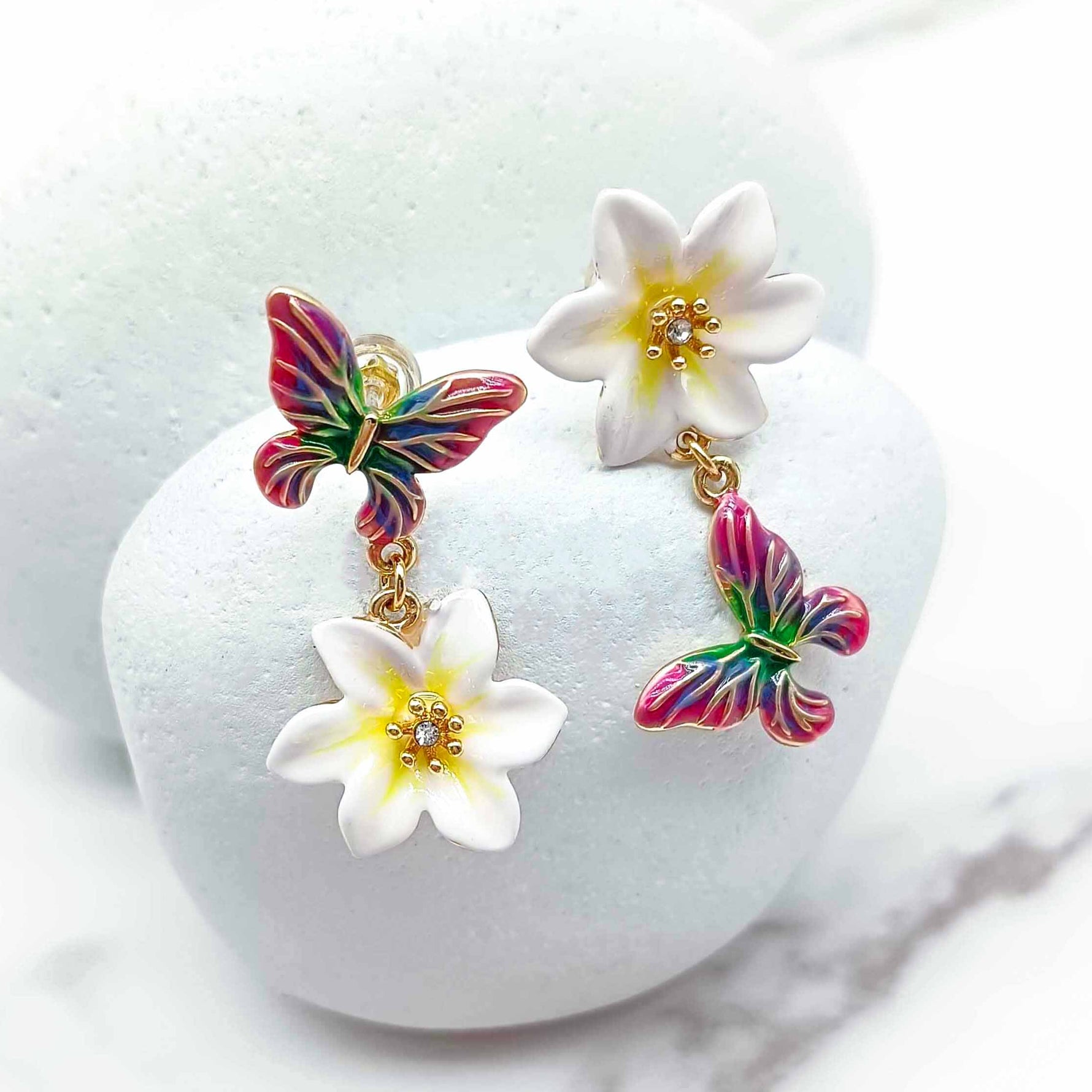 Colorful butterfly earrings with white flowers on a white background