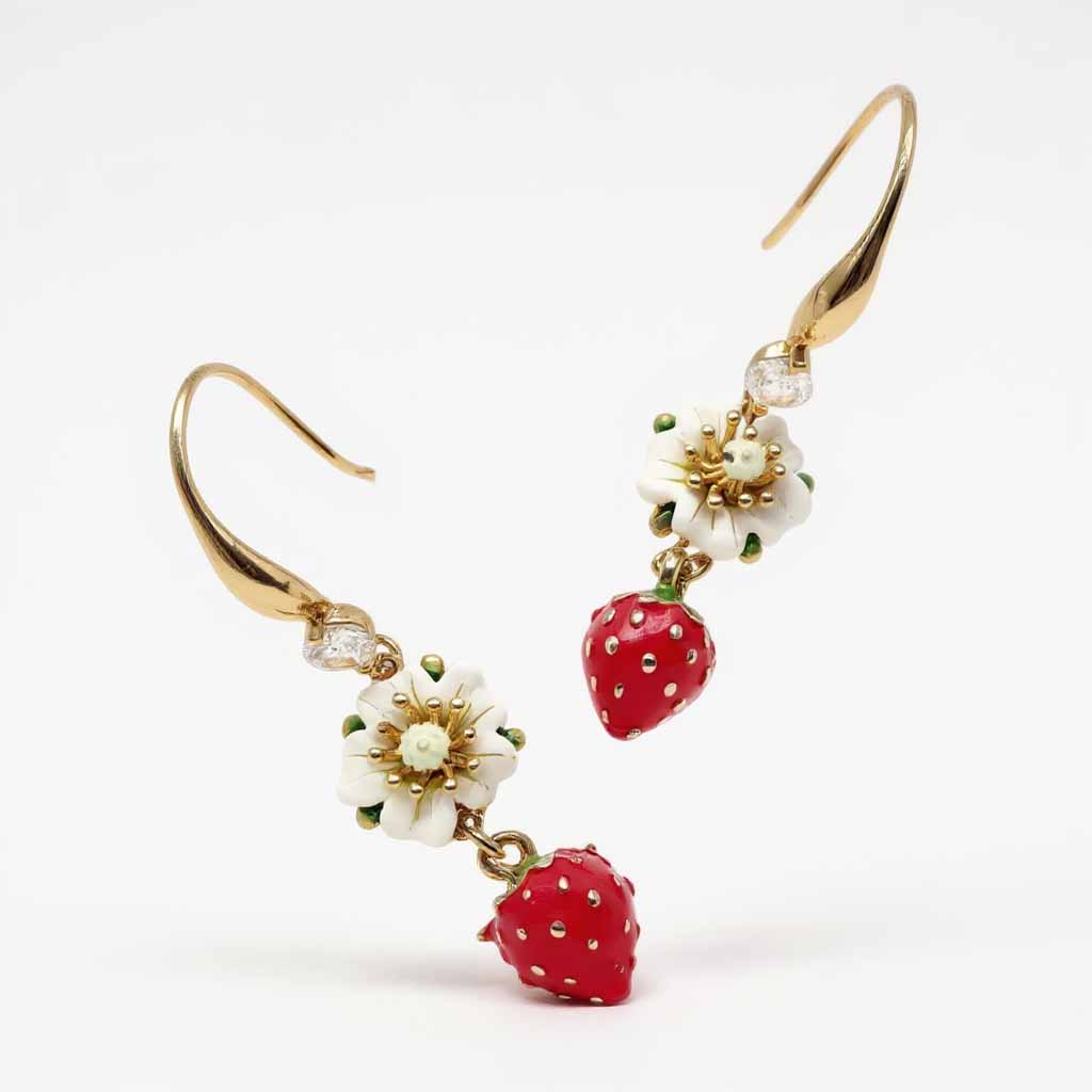 Gold earrings with strawberry and flower designs on a white background