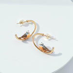 Gold hoop earrings with owl design on a white background