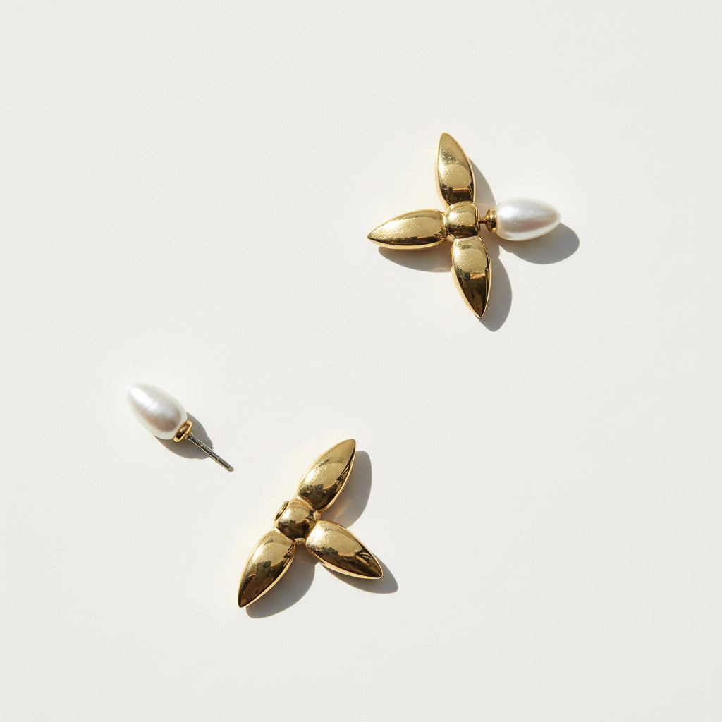 Gold earrings with pearl-like elements on a light background