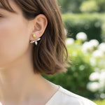 Close-up of a person wearing earrings with a blurred natural background