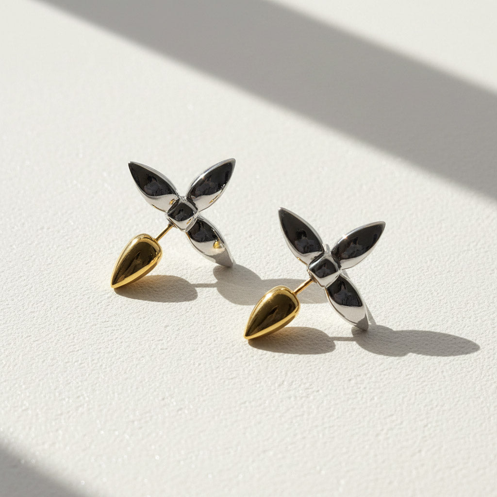 Pair of earrings with gold and silver leaf-like design on a light background