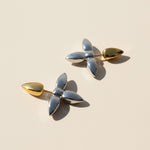 Pair of earrings with gold and silver design on a beige background