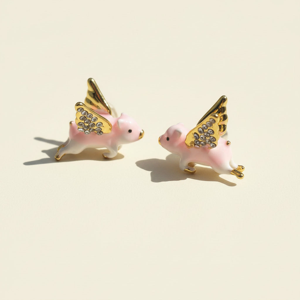 Two pink pig figurines with gold wings on a beige background