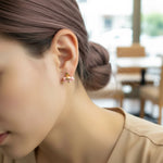 Close-up of a person wearing a small earring with a blurred indoor background
