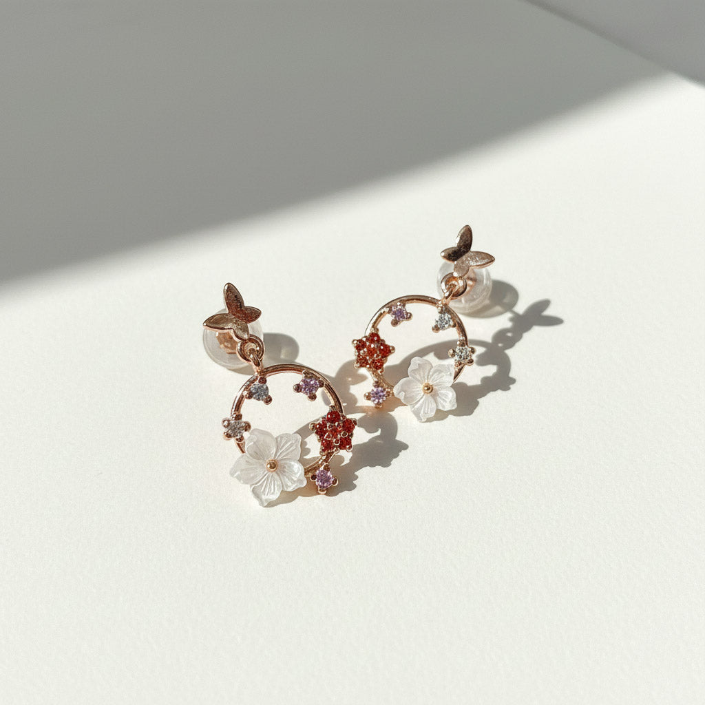 Decorative earrings with floral and butterfly designs on a light background