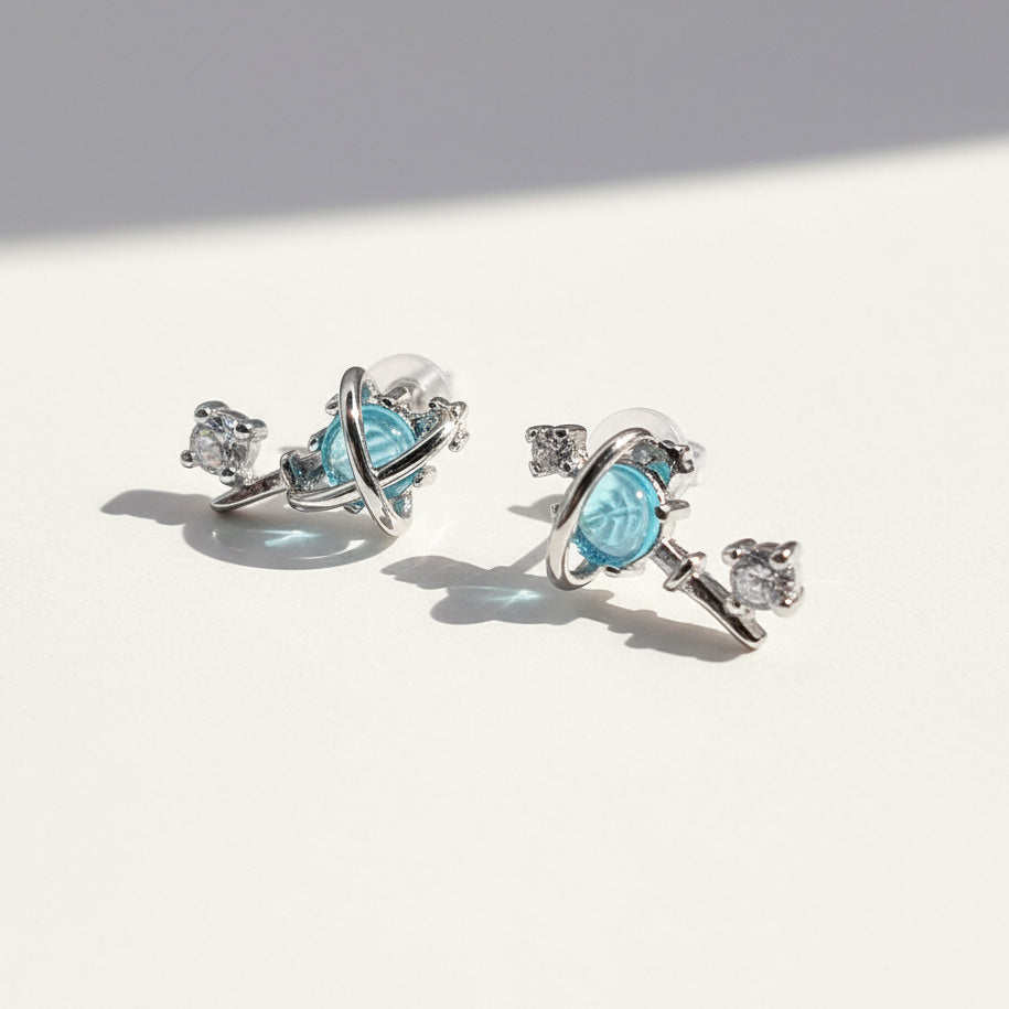 Pair of silver earrings with blue gemstones on a light background