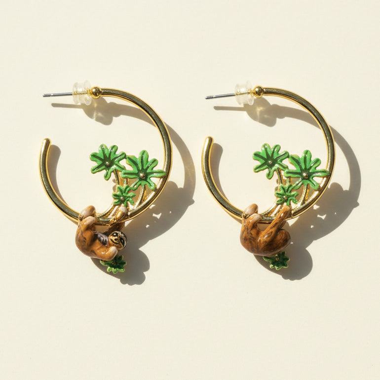 Gold hoop earrings with sloth and palm tree designs on a beige background